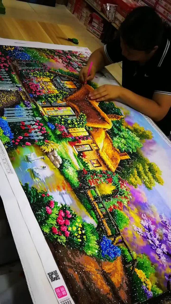 a woman working on a very large diamond art picture